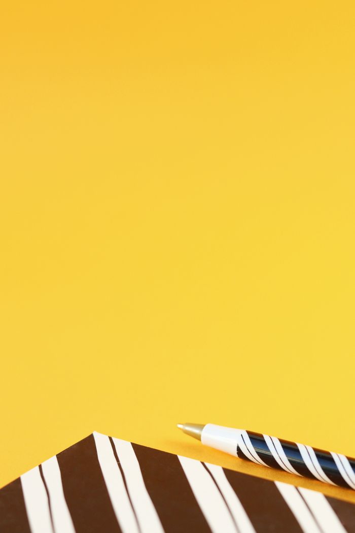 Minimalist composition with notebook and pen on vibrant yellow background, ideal for creative projects.